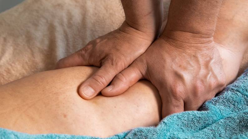 Man giving a massage to a leg with two hands.